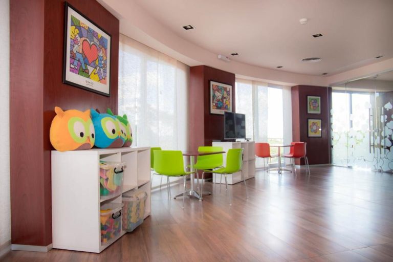 Sala de juegos infantiles con sillas coloridas y peluches búho en 7 Saltos Resort