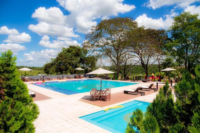 Piscina exterior con tumbonas y sombrillas rodeada de vegetación tropical en 7 Saltos Resort