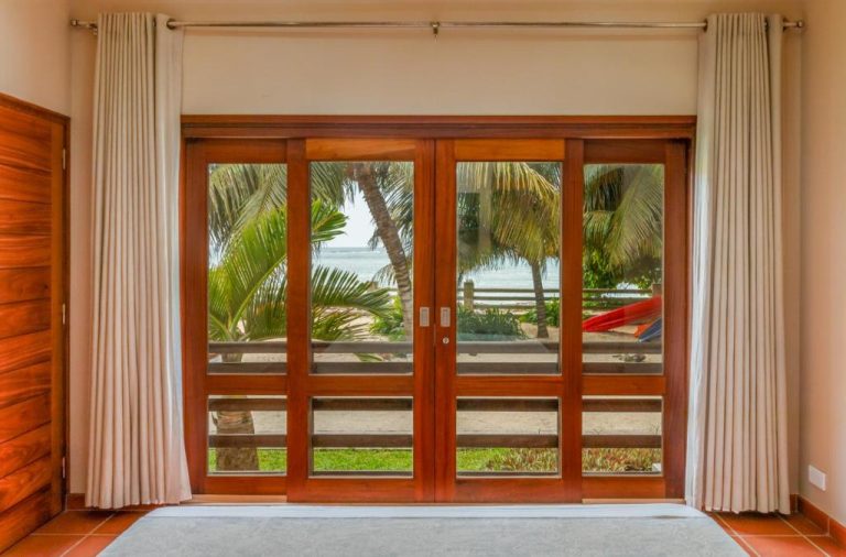 Habitación con puertas de madera y vistas a la playa y palmeras en el Hotel Fleur de Sel