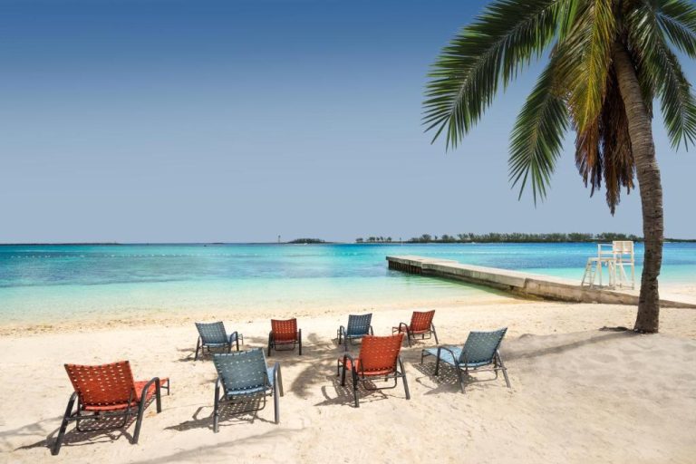 Playa privada con sillas de descanso y palmera del Holiday Inn Express & Suites Nassau en Bahamas