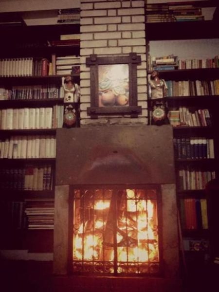 Salón acogedor con chimenea encendida y biblioteca del Hospedaje Del Pilar en Magdalena del Mar