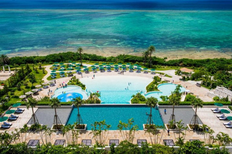 Vista aérea de las piscinas exteriores del Hotel Monterey Okinawa Spa & Resort con el mar turquesa al fondo