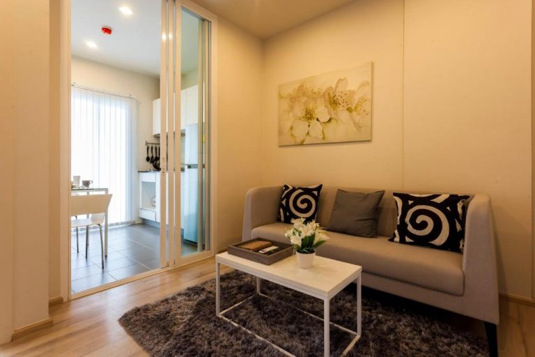 Sala de estar moderna con sofá gris y mesa de centro blanca en The Base Downtown Phuket Town