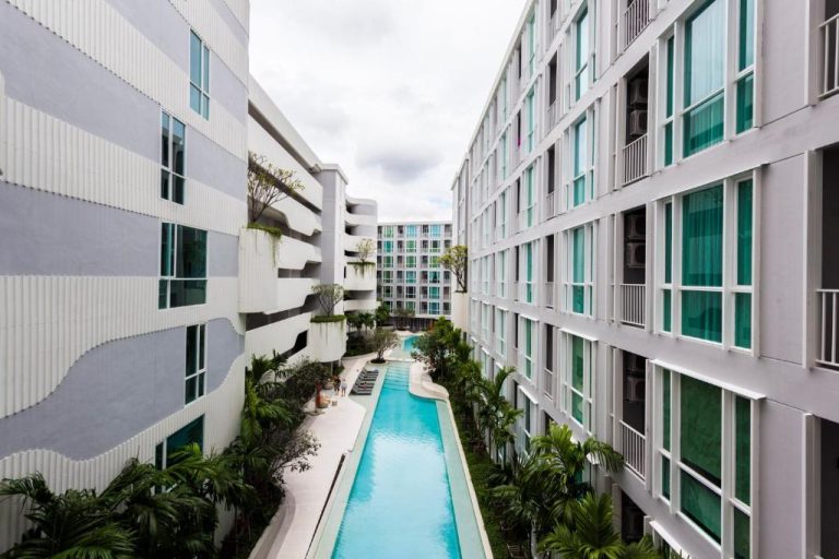 Piscina larga interior rodeada de palmeras en The Base Downtown Condo de Phuket Town