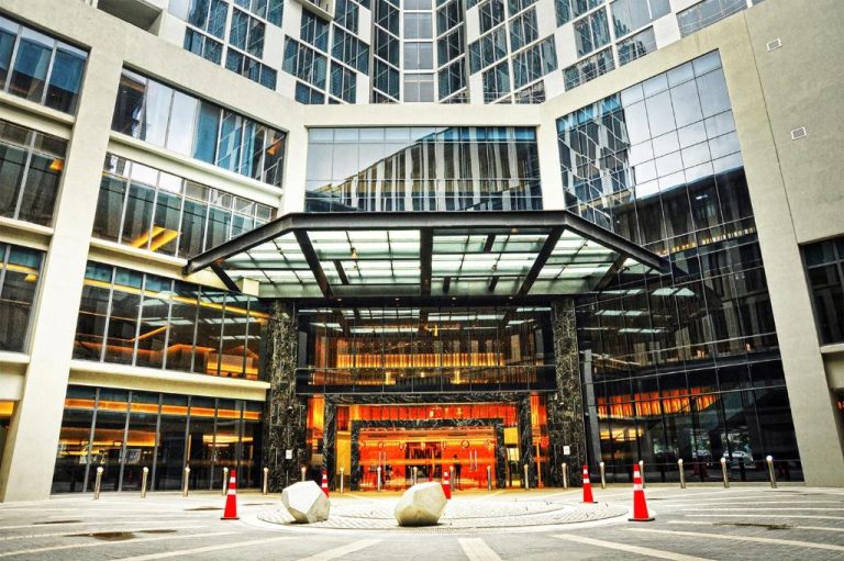 Entrada principal y fachada moderna del Bai Hotel Cebu con conos de tráfico y acceso al lobby iluminado