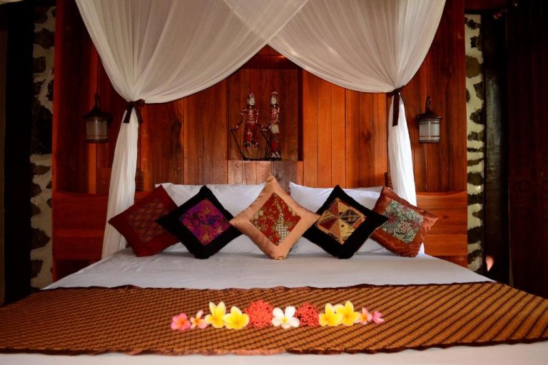 Habitación con cama de dosel y decoración balinesa tradicional en Tangkoko Sanctuary Villa