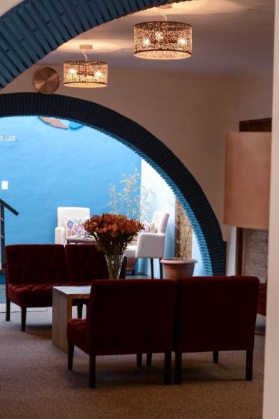 Elegante salón con arco decorativo de ladrillo y sillones rojos en Cooper Hotel Boutique
