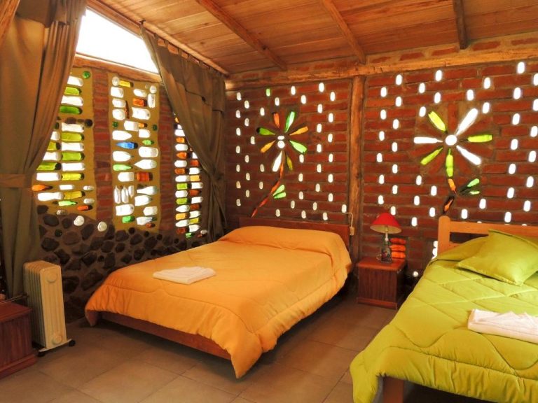 Habitación doble de La Casta con paredes decorativas de botellas de colores y techo de madera