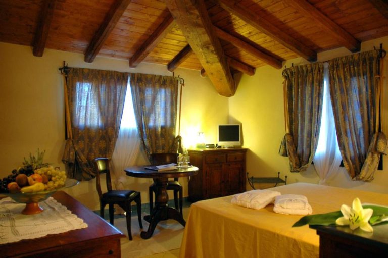 Habitación doble rústica con vigas de madera y decoración tradicional sarda en Hotel Su Lithu
