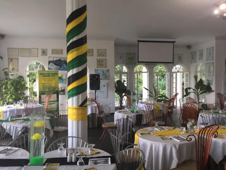 Salón de eventos decorado con los colores de Jamaica en el Jamaica Palace Hotel con mesas vestidas