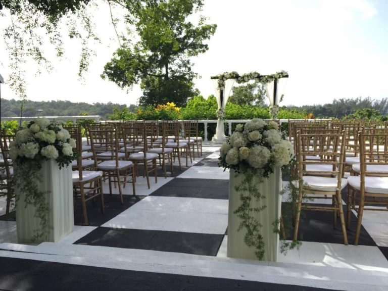 Ceremonia de boda al aire libre con arco floral y sillas doradas en Jamaica Palace Hotel