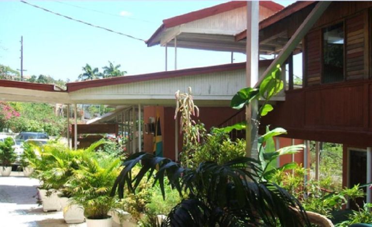 Fachada exterior de madera del Verney House Resort rodeada de exuberante vegetación tropical y jardines