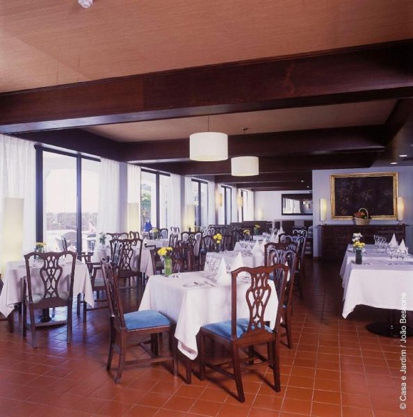 Restaurante interior elegante con mesas vestidas de blanco y sillas de madera en Pousada Forte Horta