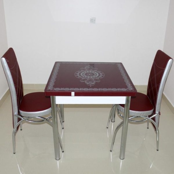 Comedor con mesa y sillas tapizadas en rojo y cromo del Manarat Manah Hotel Apartments
