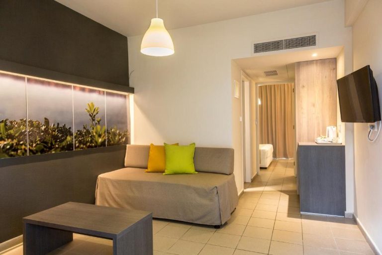 Salón de suite familiar con sofá, mesa de centro y acceso al dormitorio en Mayfair Gardens