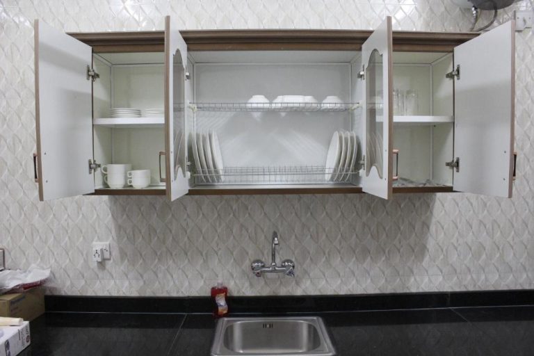 Cocina equipada con armarios abiertos y vajilla en Manarat Manah Hotel Apartments