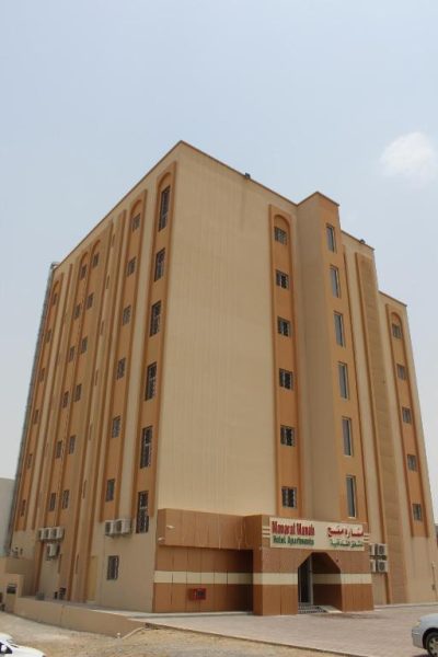 Fachada exterior del Manarat Manah Hotel Apartments, edificio de apartamentos de varios pisos en tono arena