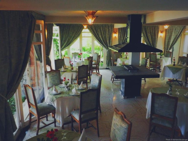 Elegante restaurante interior del Auberge des Cascades Imouzzer con mesas vestidas y vistas al jardín
