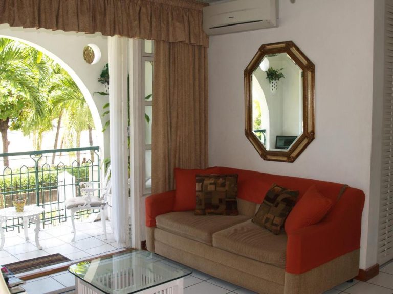 Sala de estar con sofá rojo y balcón tropical en Sandcastles Resort Ocho Rios, Jamaica