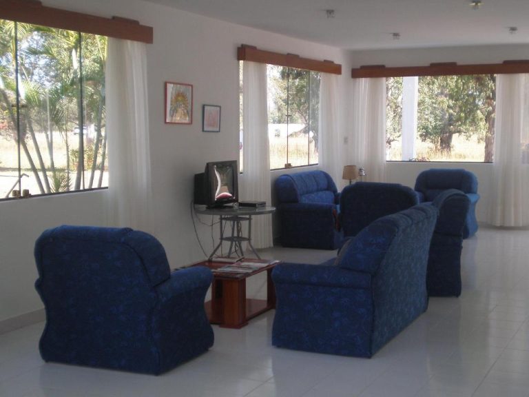 Sala de estar con sofás azules y televisión en el Hotel Ruta del Sol con vistas al jardín