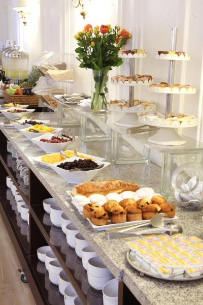 Amplio buffet de desayuno con bollería, frutas y pasteles en el Hotel MR Express Santiago