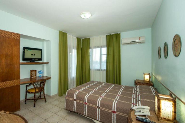 Habitación doble estándar con cama matrimonial y cortinas verdes en Divi-Divi Praia Hotel