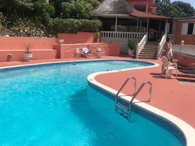 Piscina exterior de agua turquesa con terraza roja en Verney House Resort Jamaica