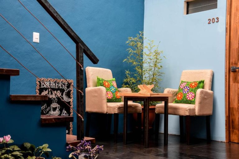 Área común con sillas y mesa de madera junto a señal de desayuno en Cooper Hotel Boutique