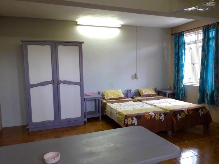 Habitación doble con dos camas, armario lila y cortinas azules en el Hotel Centraville