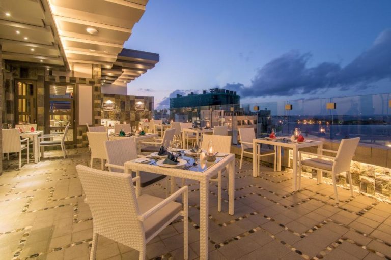 Terraza restaurante del Samann Grand con mesas elegantes, vistas panorámicas y ambiente nocturno iluminado