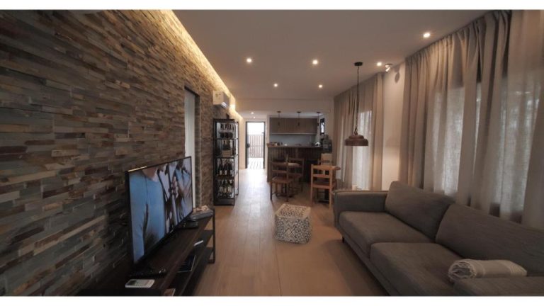 Amplio salón con pared de piedra, televisor y zona de comedor con bodega en Pizzorno Lodge & Wine