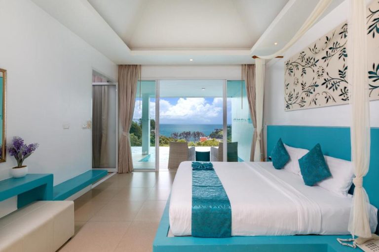 Habitación de lujo con cama dosel azul turquesa y vistas panorámicas al mar en Amala Grand Bleu Resort
