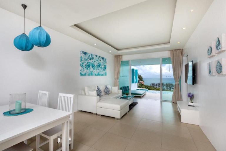 Salón luminoso con sofá blanco y vistas al mar en Amala Grand Bleu Resort Hilltops SHA
