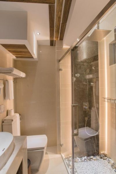 Baño de lujo con ducha de lluvia y revestimiento de mármol oscuro en el Samann Grand