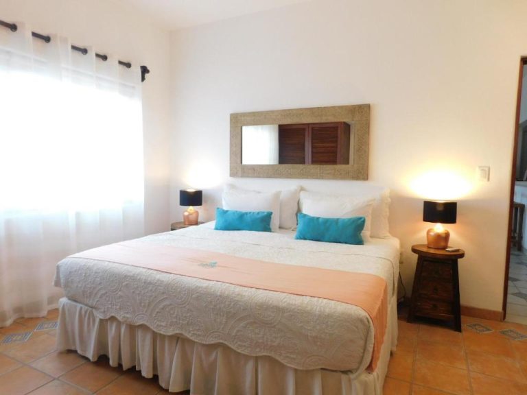Habitación doble con cama matrimonial y almohadas azules en Fabiola Condo Hotel