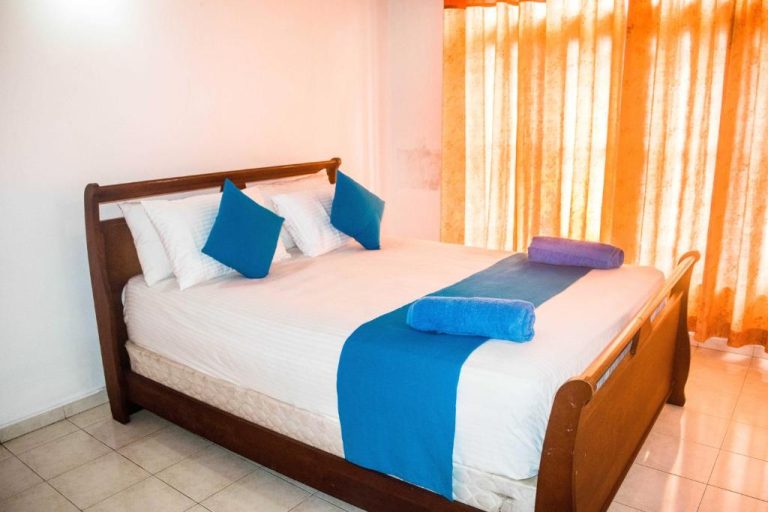 Habitación doble con cama de madera y cojines azules en 360 Beach Residence