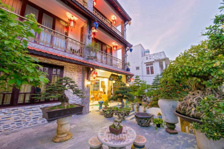 Jardín exterior con colección de bonsáis y terraza iluminada del Bonsai Villa Hoi An en Vietnam