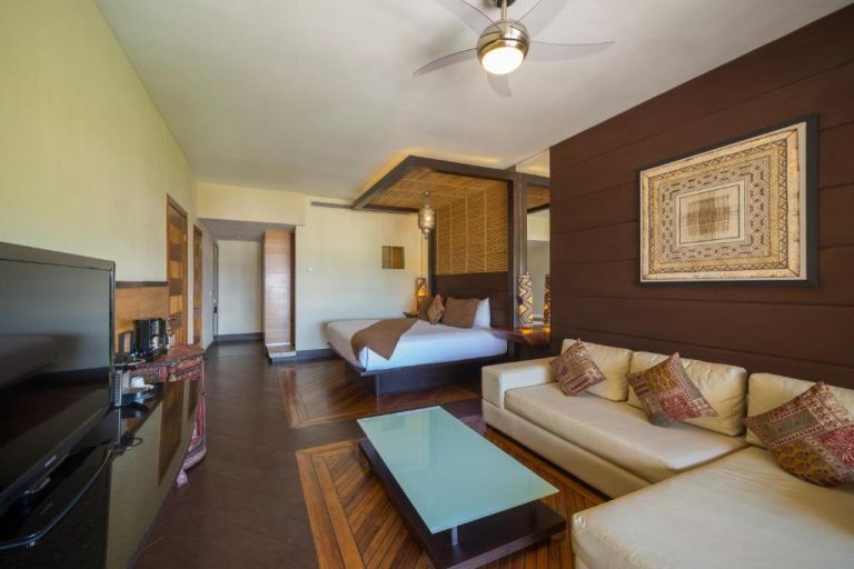 Suite con cama de dosel, sofá y sala de estar en La Divina by Aldea Thai con decoración tropical