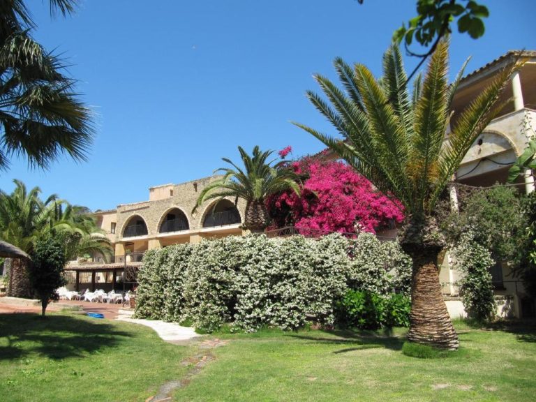 Jardín exterior con palmeras y buganvillas del Hotel Costa dei Fiori en Cerdeña
