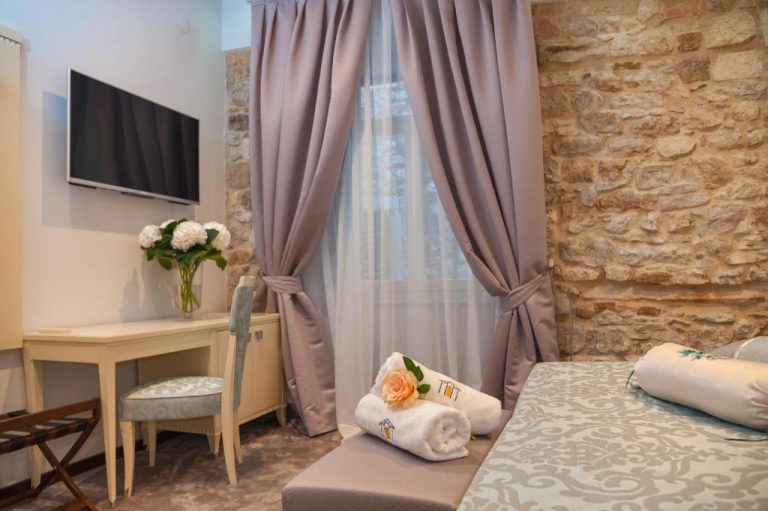 Habitación elegante con pared de piedra y cama doble en Heritage Hotel Antique Split, Croacia