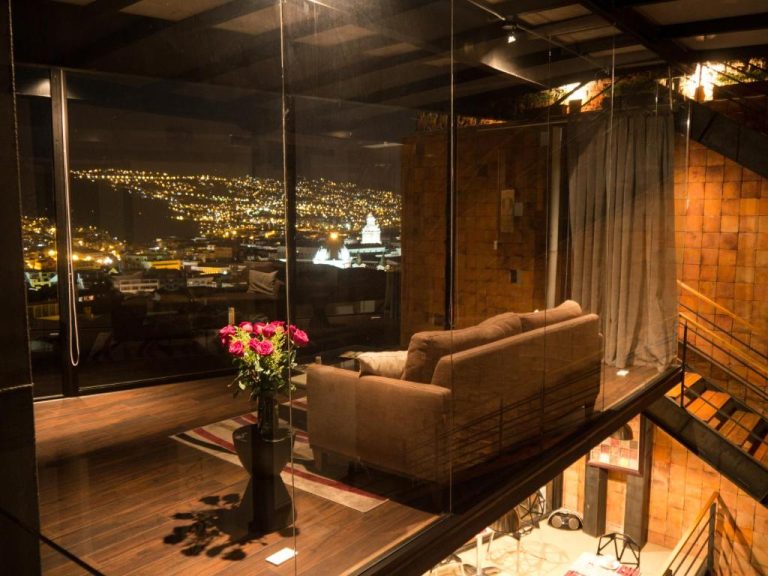 Sala de estar con sofá y vista panorámica nocturna de la ciudad en Hotel Casa Gardenia