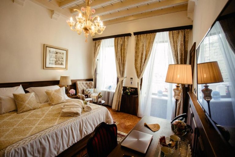 Habitación de lujo con cama doble y lámpara de araña dorada en Heritage Hotel Cardo