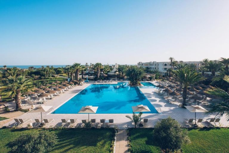 Piscina exterior con tumbonas y palmeras del Iberostar Waves Mehari Djerba con vistas al mar