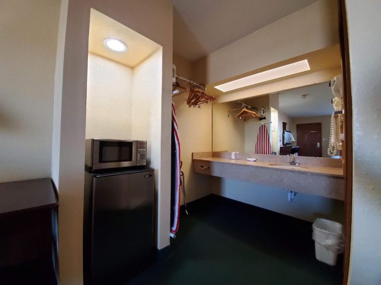 Zona de baño con lavabo, microondas, nevera y armario con perchas en el Cuba Inn