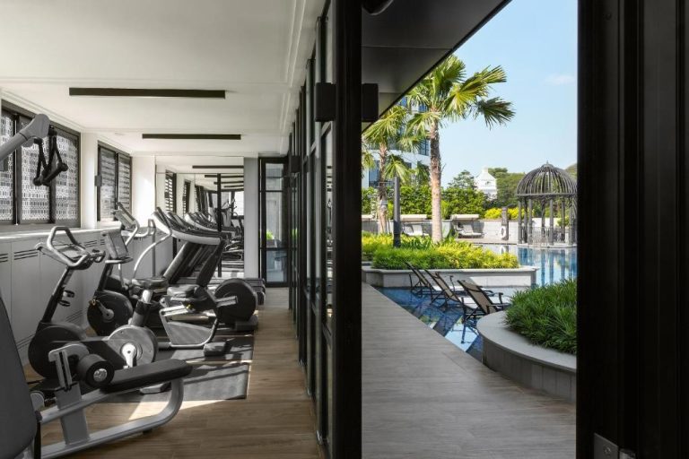 Gimnasio moderno con vistas a la piscina exterior y jardines tropicales del Grand Park City Hall