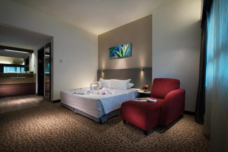 Habitación deluxe con cama doble y sillón rojo en Crown Regency Serviced Suites Kuala Lumpur