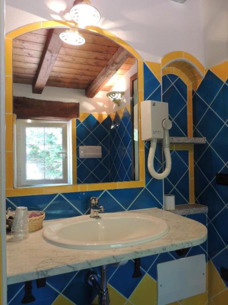 Baño decorado con azulejos azules y amarillos y techo de madera en Hotel Su Lithu