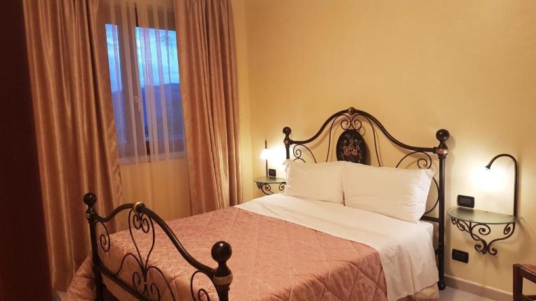 Habitación doble con cama matrimonial de forja y decoración clásica en el Hotel Le Tre Rose