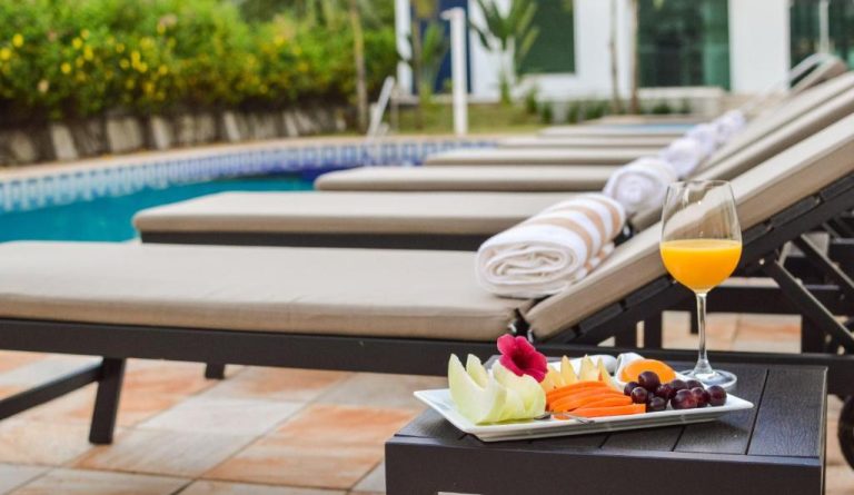 Tumbonas junto a la piscina con bandeja de frutas y zumo en Bisinii Boutique Hotel
