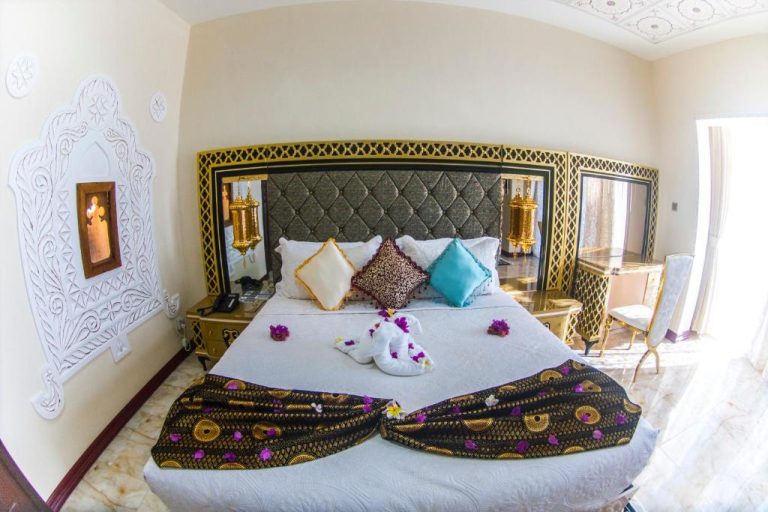 Habitación de lujo con cama doble y decoración arabesca dorada en Madinat Al Bahr Business & Spa Hotel